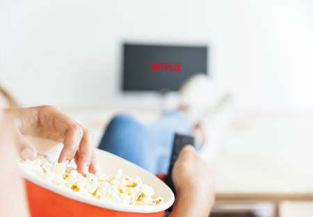 crop woman eating popcorn watching series living room. High quality beautiful photo conceptの写真素材