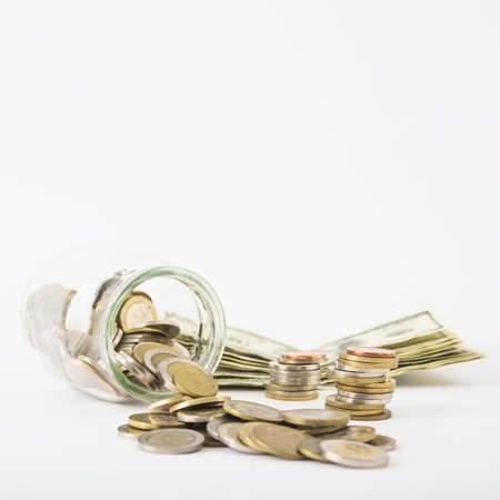 coins scattered from jar with paper money table. High quality beautiful photo conceptの写真素材