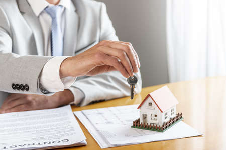 person holding house keys toy model house desk. High quality beautiful photo conceptの写真素材