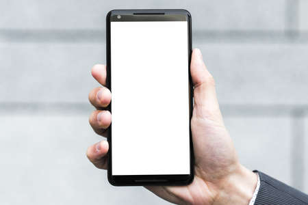 businessperson s hand showing white display screen smartphone against blurred backdrop. High quality...