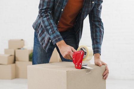 close up man sealing cardboard box with duct tape. High quality beautiful photo concept