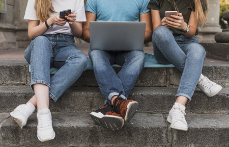 teens sitting stairs working phones laptop. High quality beautiful photo conceptの写真素材