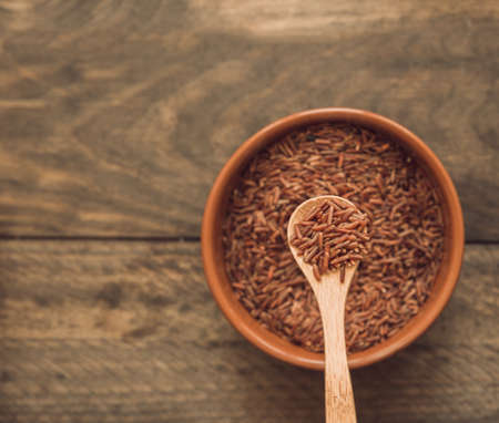 red jasmine rice grains spoon bowl against wooden backdrop. High quality beautiful photo conceptの写真素材