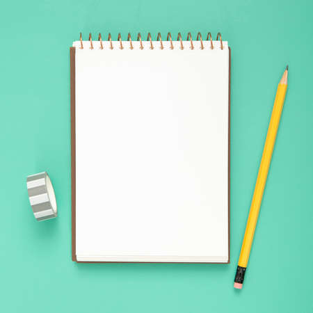 desk arrangement with empty notepad blue background