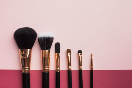 flat lay frame with make up brushes pink background