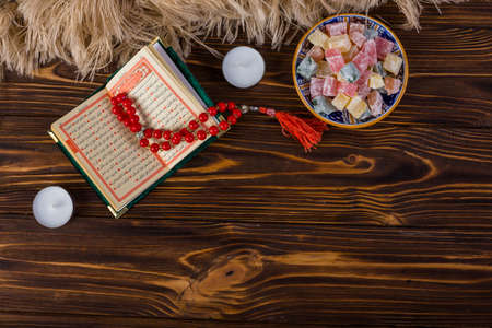 bowl multicolored lukum red holy rosary beads kuran with candles wooden surfaceの写真素材