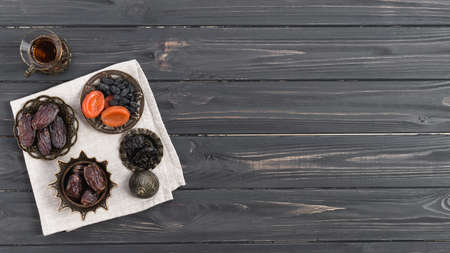 tea glass with whole juicy dates dried fruits napkin wooden desk. High quality photoの写真素材