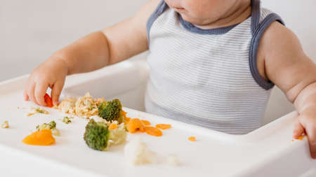 cute baby boy highchair choosing what eat. High quality photoの写真素材