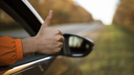 man giving thumbs up out his car while road trip. High quality beautiful photo conceptの写真素材
