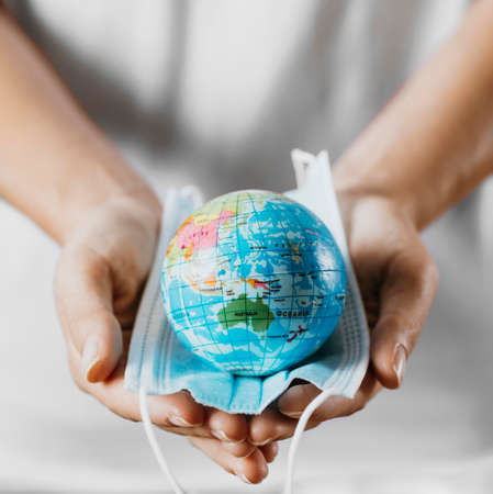 high angle person holding medical mask with earth globe. High quality photoの写真素材