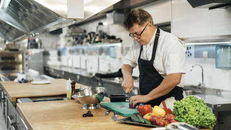male chef with apron chopping vegetables. High quality beautiful photo concept
