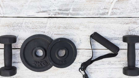 dumbbells weight plates fitness strap white wooden textured background. High quality photoの写真素材
