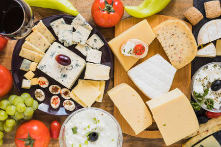 cheese blocks slices with tomatoes grapes green chili pepper table. High quality photoの写真素材