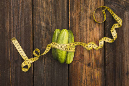 high angle view fresh cucumbers measuring tape wooden background. High quality beautiful photo conceptの写真素材