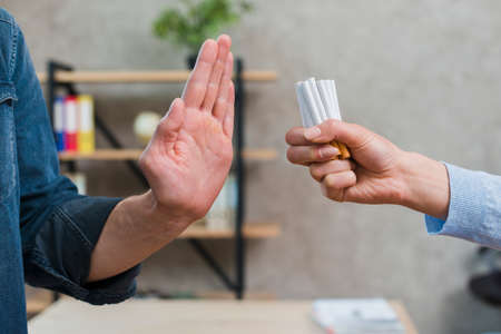 man refusing bunch cigarettes offered by his female friend. High quality photoの写真素材