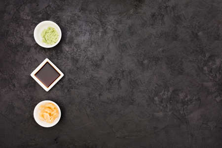 marinated ginger soy sauce wasabi bowl arranged row textured black surface. High quality photo