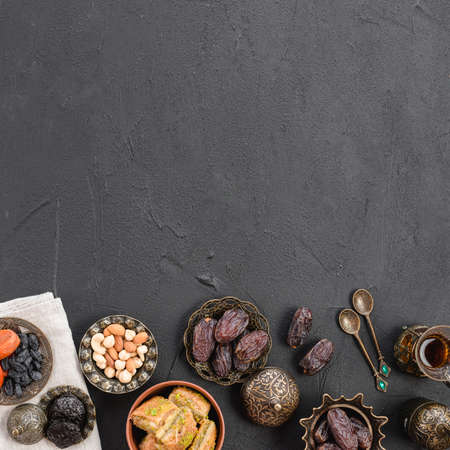 overhead view dates nuts baklava metallic plates black concrete textured backdrop with copy space....