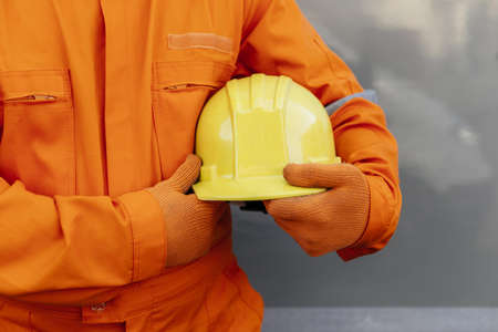 front view worker in uniform holding hard hatの写真素材