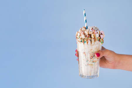 front view hand holding milkshake with blue background. High quality beautiful photo concept