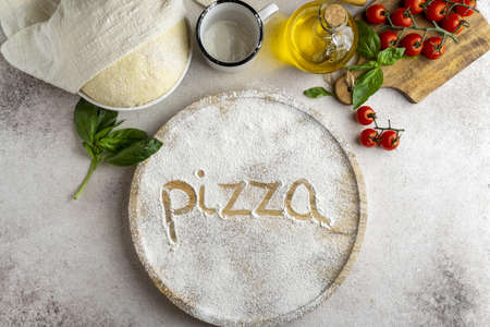 flat lay pizza dough with wooden board word written flour.の写真素材