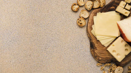 emmental cheese gouda cheese with slices coaster with bread slices walnut beige textured backdrop....