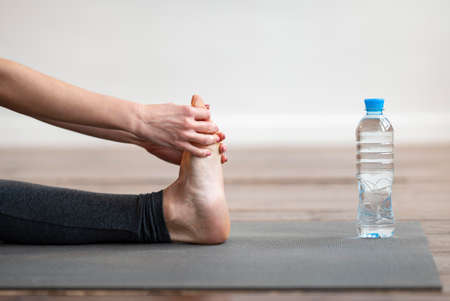 side view woman stretching yoga mat with water bottle. High quality photo