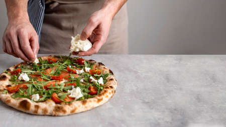 man putting mozzarella baked pizza dough with smoked salmon slices. High quality photoの写真素材