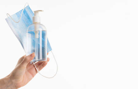 hand holding medical mask with hand sanitizer bottle. High quality photoの写真素材