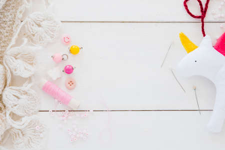 colorful beads spool needle rag unicorn white wooden desk. High quality photoの写真素材