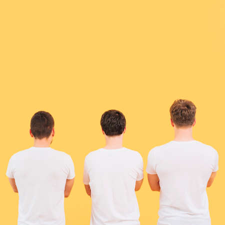 rear view men white t shirt standing against yellow background. High quality photoの写真素材