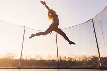 active little girl jumping trampoline against sky. High quality photoの写真素材