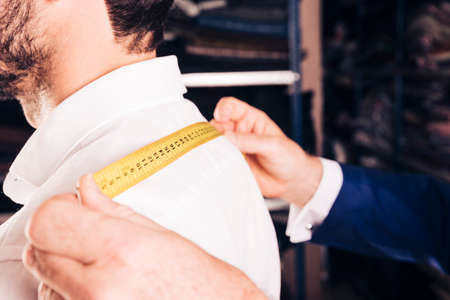 fashion designer taking measurement his customer s back with yellow measuring tape. High quality photoの写真素材