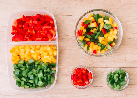 organic fresh chopped red green yellow bell peppers tiffin box glass bowls wooden desk. High quality photoの写真素材