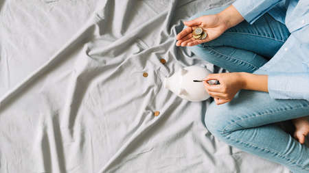 elevated view person s hand inserting coins piggybank. High quality photo