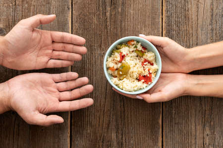 hand giving bowl food needy person. High quality photoの写真素材