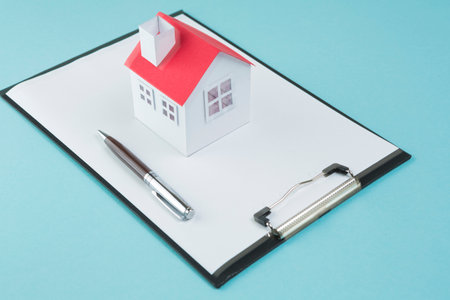 small house model pen blank clipboard blue backdrop. High quality photoの写真素材
