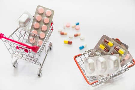 pills medicine blisters inside two shopping cart white background. High quality photoの写真素材