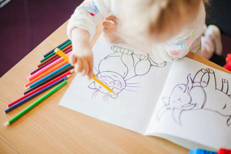 girl holding pencil sitting table. High quality photoの写真素材