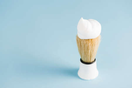 overhead view classic shaving brush with white foam against blue background. High quality photoの写真素材