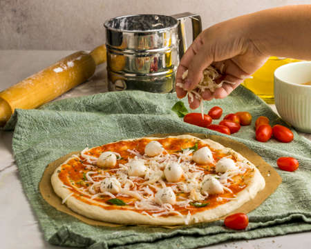 person sprinkling mozzarella cheese pizza. High quality photoの写真素材