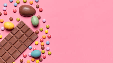 chocolate bar easter eggs gem candies pink background. High quality photoの写真素材