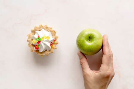 human hand holding green apple near tart cake backdrop. High quality photoの写真素材