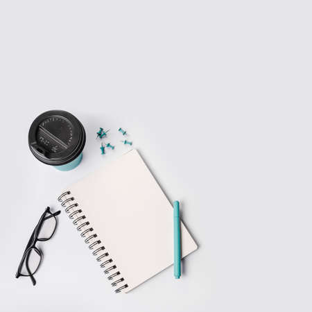 overhead view disposable coffee cup push pins pen eyeglasses spiral notepad white background. High quality photoの写真素材