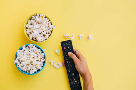 crop hand remote control near popcorn. High quality photo