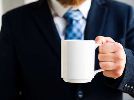 elegant man holding up white mug. High quality photoの写真素材