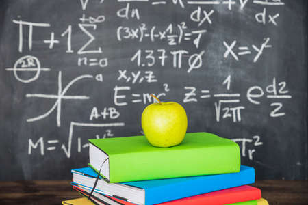 apple books pile near chalkboard. High quality photo