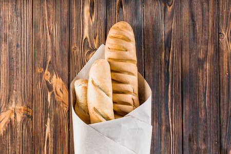 baguettes wrapped paper wooden background. High quality photoの写真素材