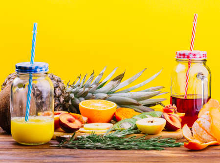fruits rosemary juice mason jar chopping board against yellow backdrop. High quality photoの写真素材
