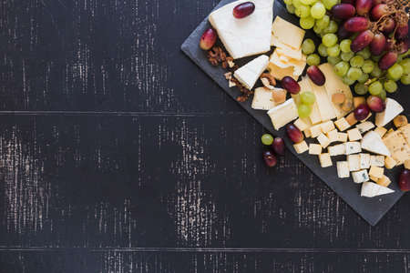 variety cheese blocks with grapes black textured backdrop. High resolution photoの写真素材