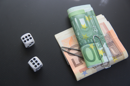 Two dice with bundles of money with black background. Wads of tickets won / wagered in the game. Top view.の写真素材